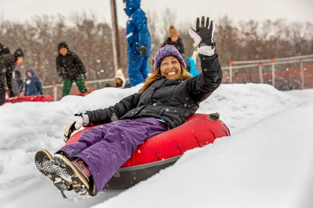 A woman smiling and having fun while riding a tube at Wilmont Mountain