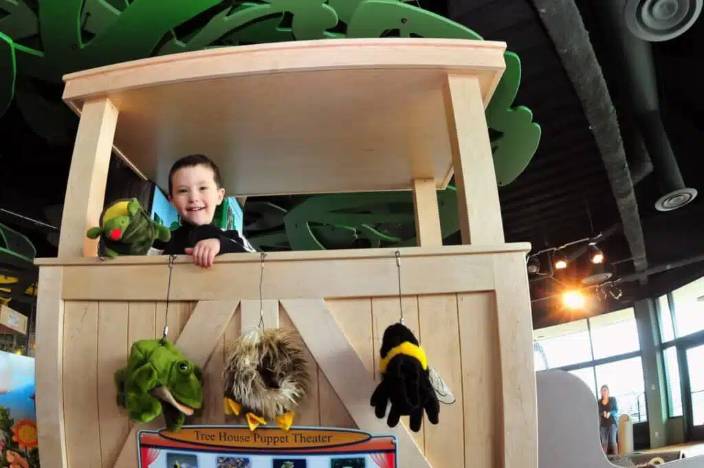 Child playing at the puppet theater inside Betty Brinn Children’s Museum.