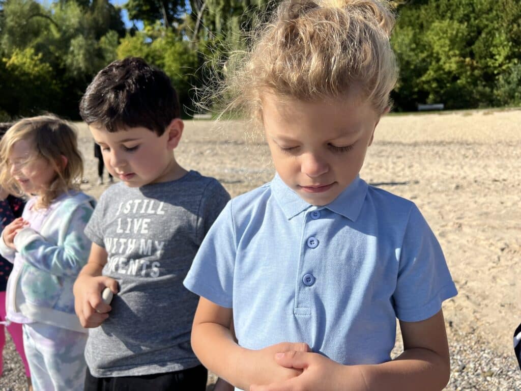 Three young students in blue, gray and printed shirts are praying.