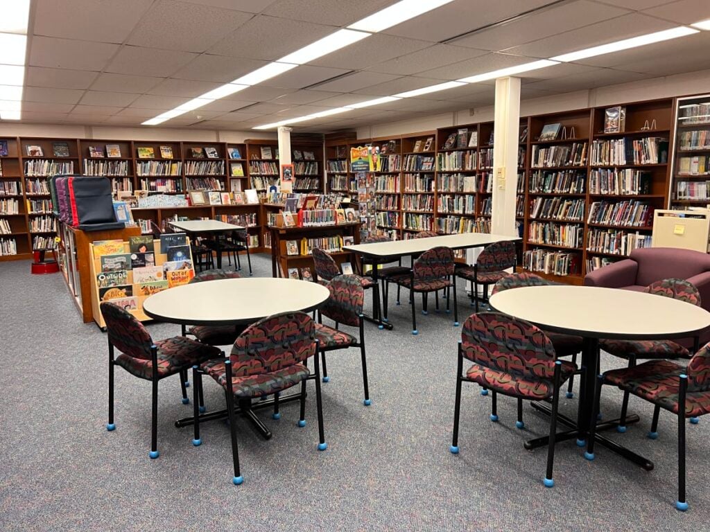 A library with cabinets full of books, tables and chairs