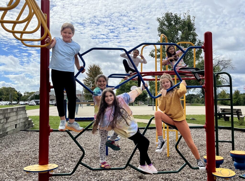 Teen students playing on an outdoor climbing bars and smiling to the camera