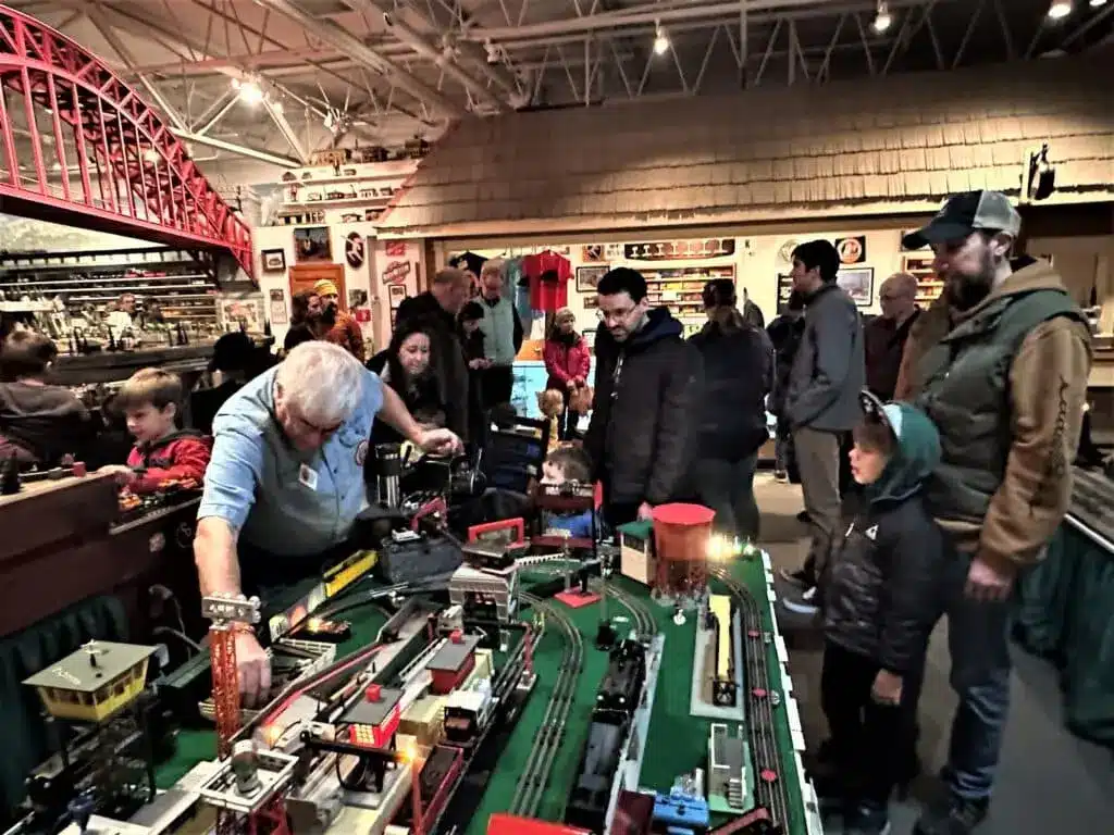A member of the Lionel Railroad Club in Milwaukee demonstrates how train works while some men are observing him