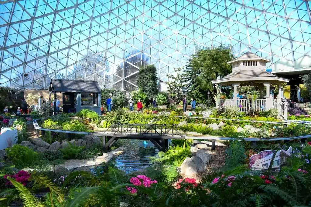 Visitors walking in the Mitchell Park Domes gardens, with a gazebo beneath the iconic glass dome structure.
