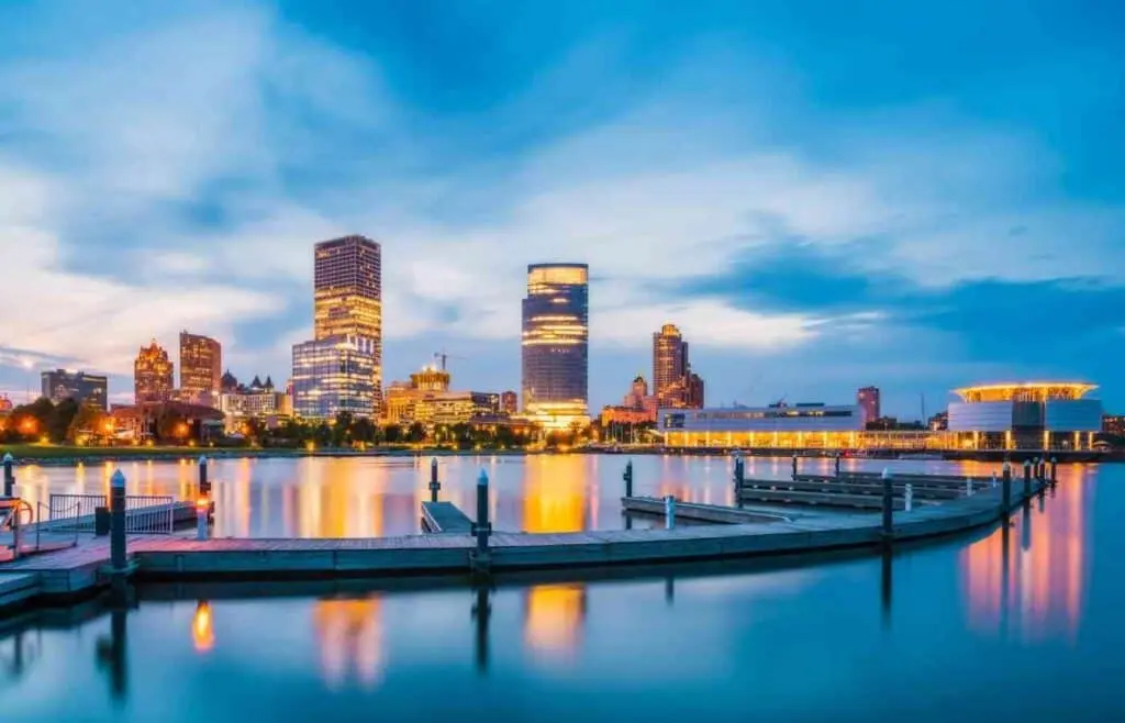 Milwaukee skyline at sunset reflected on Lake Michigan with downtown buildings and calm waterfront views.