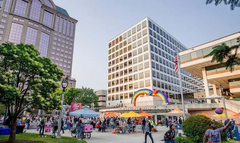 A park with a Starbucks Coffee shop, rainbow structure, trees and lots of people 