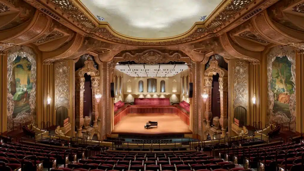 Interior of the Bradley Symphony Center for Milwaukee with empty seats, painted walls and a piano in the center of the stage.