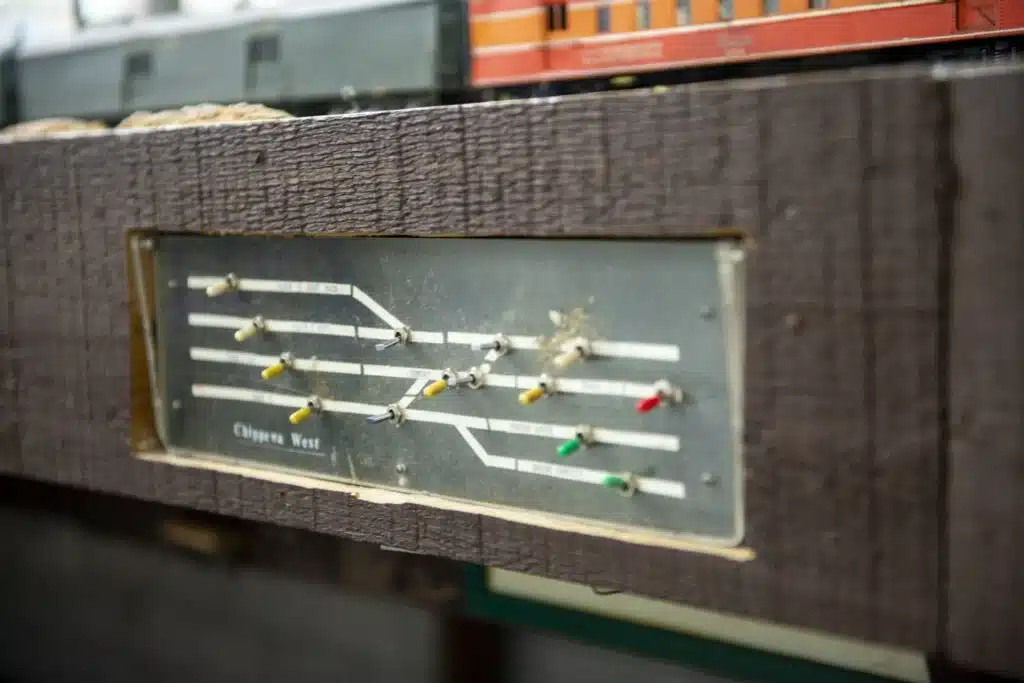 A switch panel with fourteen switches for miniature trains attached to a wood block