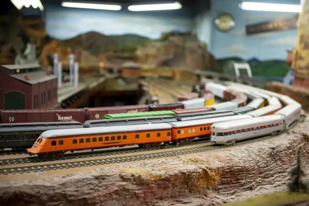 Several miniature trains traveling along curved tracks on display at the Model Railroad Club of Milwaukee