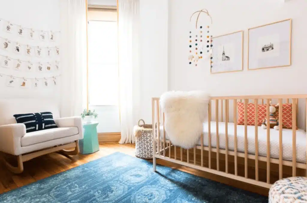 Modern gender-neutral nursery with light wood crib and blue rug
