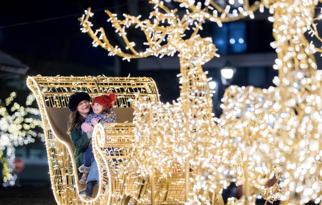 Mother and dauighter sitting on giant sleigh decorated with lights at Zeidler Union Square