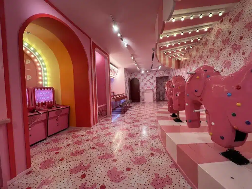 Pink carnival-style room with arcade games and giant frosted animal cracker decorations.