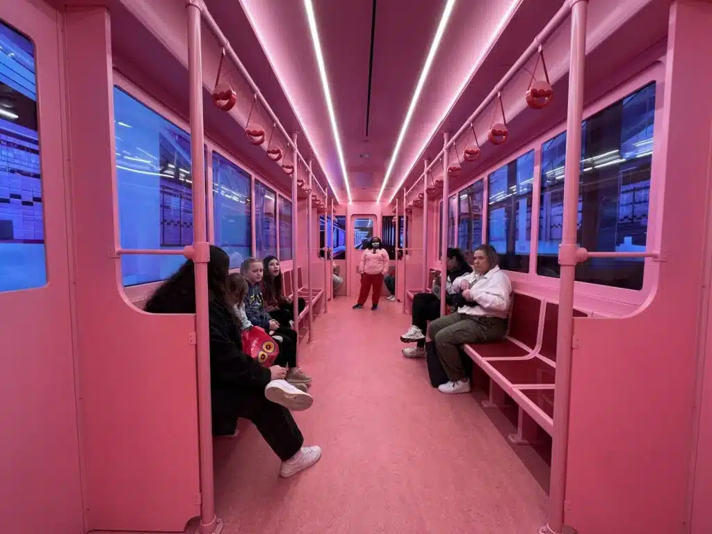 Visitors sit inside a pink subway-style trolley at the Museum of Ice Cream.