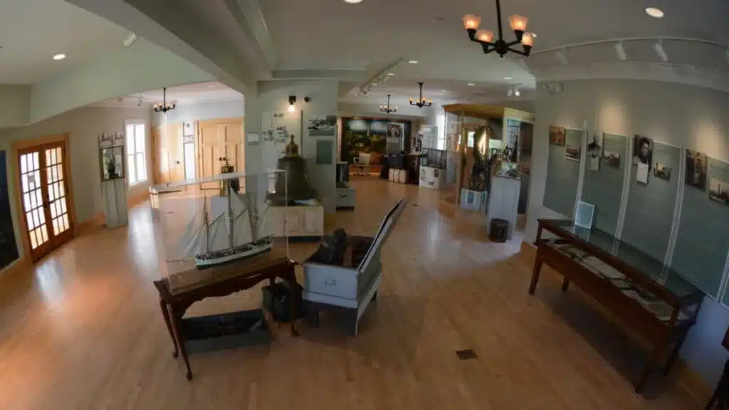 A marine museum with a model sailboat exhibit, an old bell and marine-related images