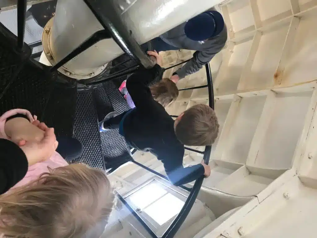 Kids being guided by their parents as they walk down a black winding staircase