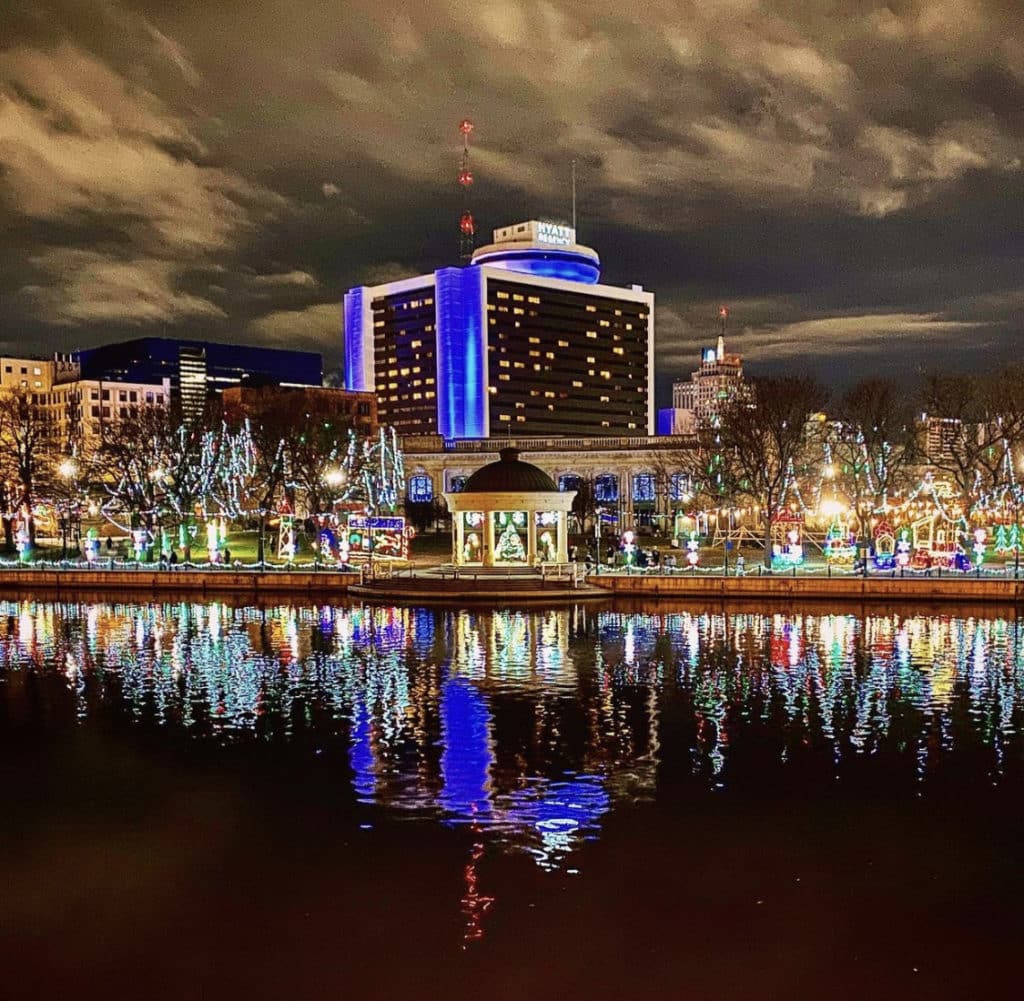 Felices Fiestas at the Marquette Park as seen across the river, with trees decorated in Christmas lights