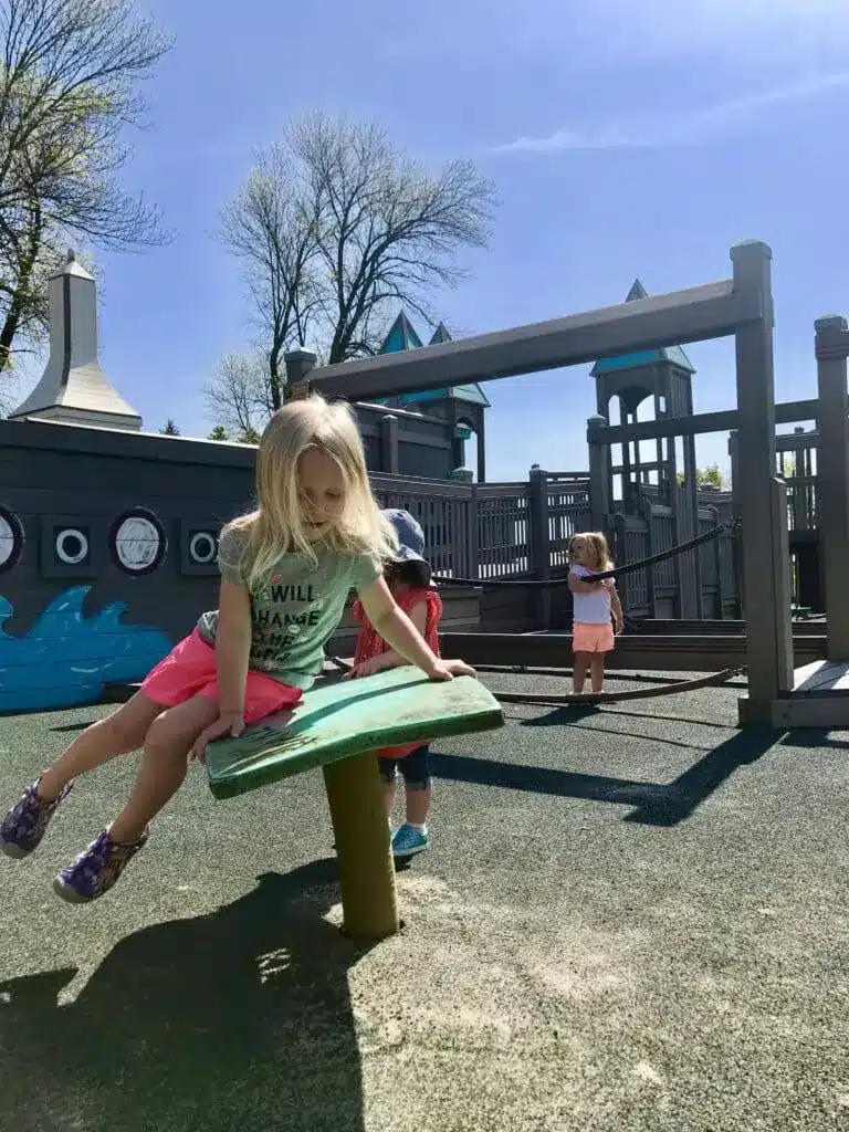 Children play on a green motion platform at the Possibility Playground