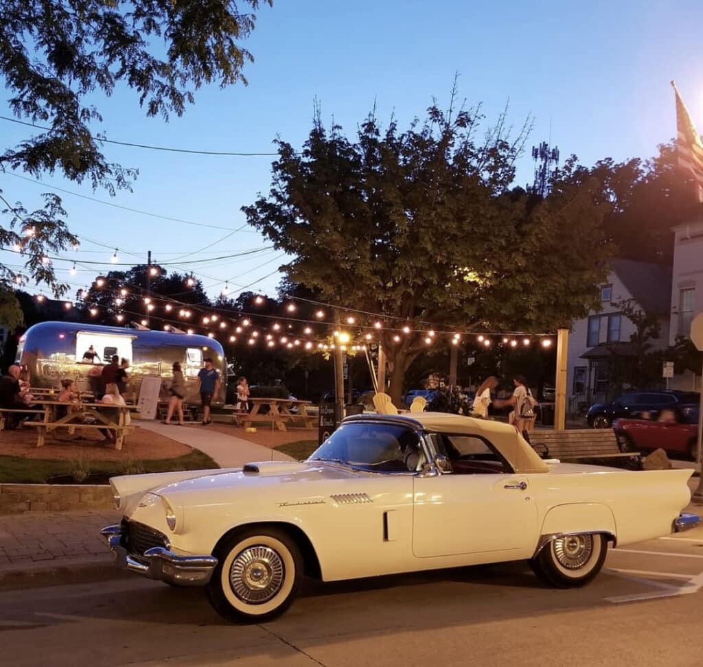 A yellow vintage convertible car near a food park
