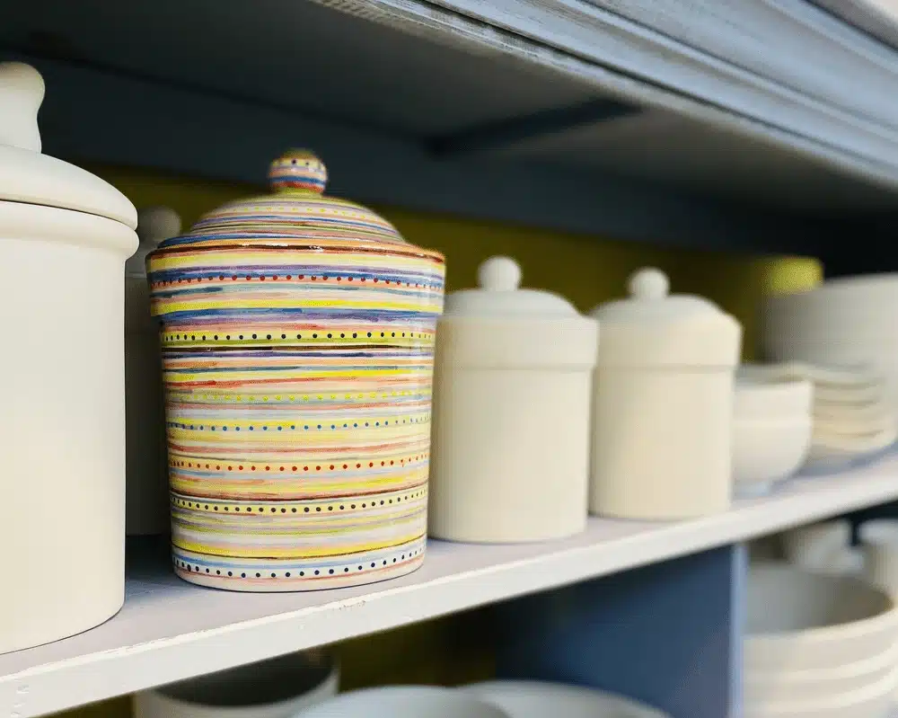 Painted ceramic jars on pottery studio shelf ready for glazing