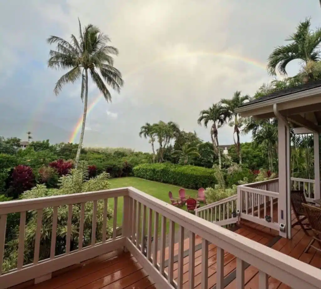 Princeville villa veranda overlooking a garden with coconut trees with a rainbow in the sky