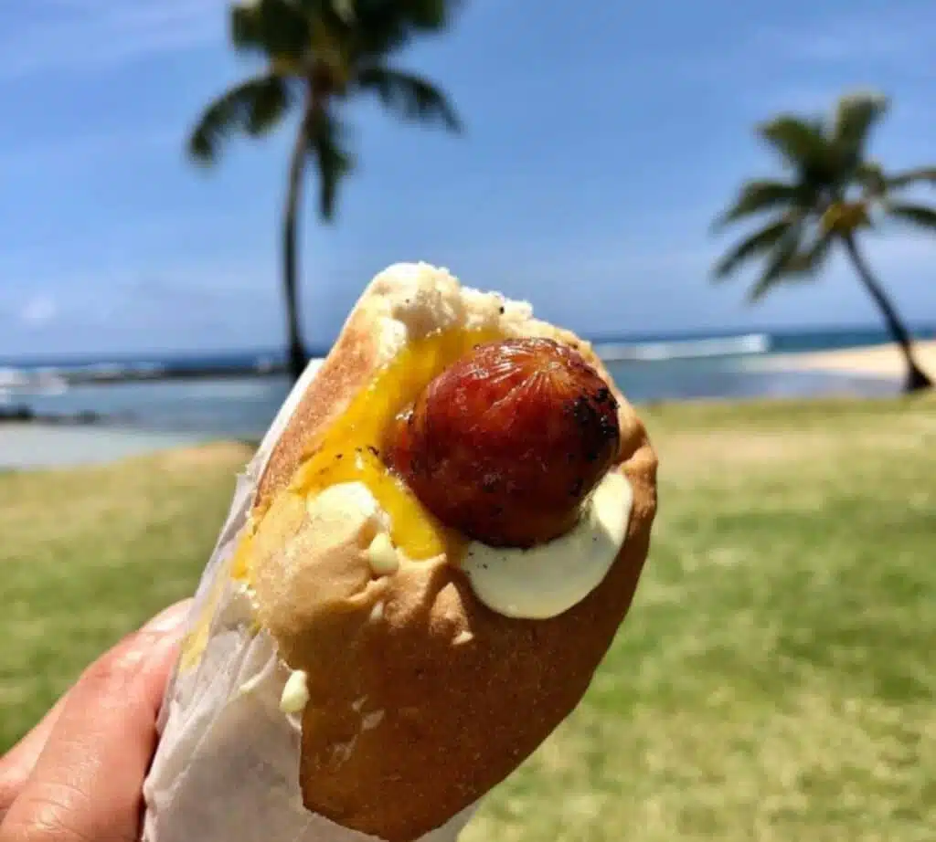 A close-up view of Puka dog with sausauge, mayo and egg placed in a bun