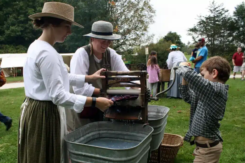 Two women and a boy washing clothes using a manual washing machine