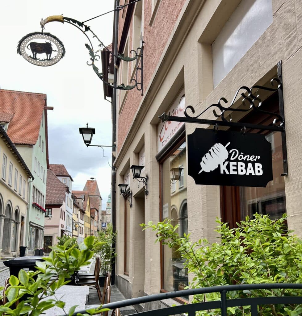 A street in Rothenburg with a shop sign for doner kebab and outdoor seating