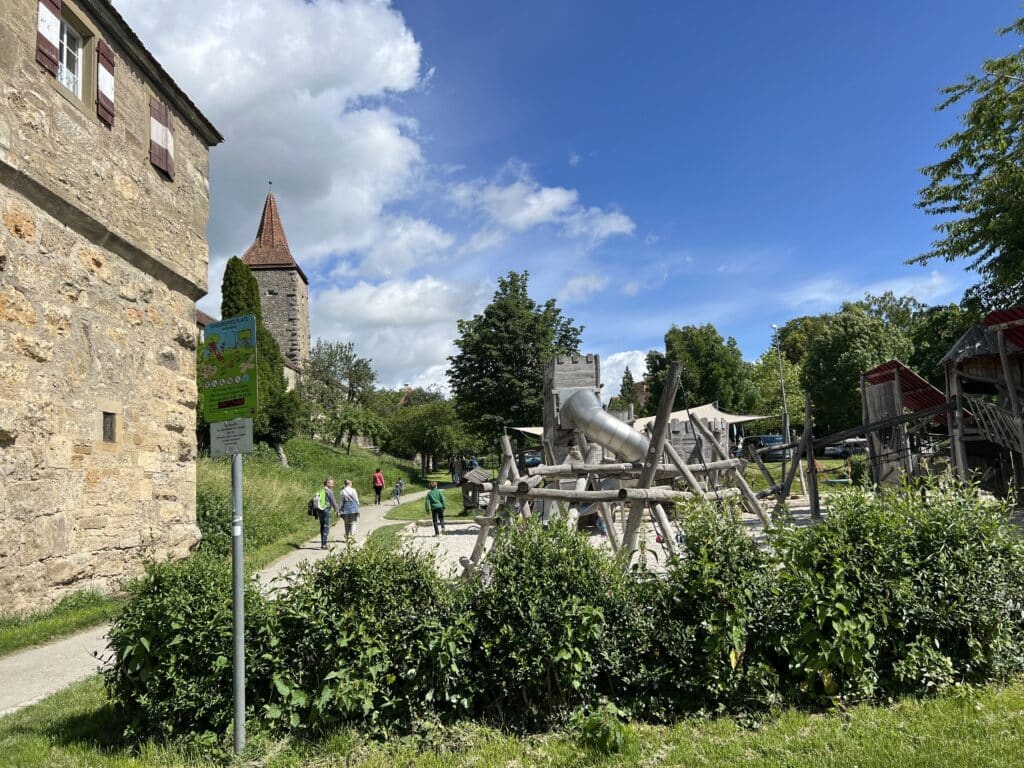 A pathway towards a tower with red roof and a partial view of the city walls