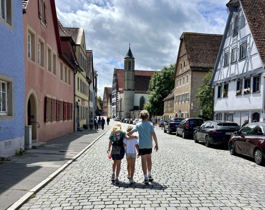Three kids walking the cobblestones of Rothenburg Ob Der Tauber during  summer