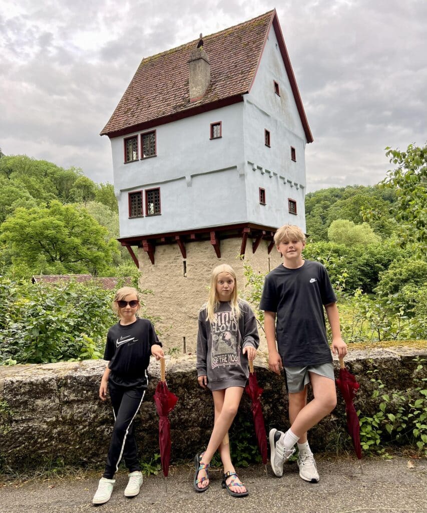 Three kids each holding red umbrellas and standing in front of the Toppler Castle