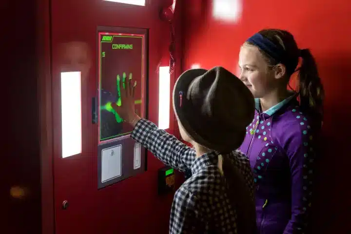 Two kids use the fingerprint-activated spy booth inside SafeHouse Milwaukee.