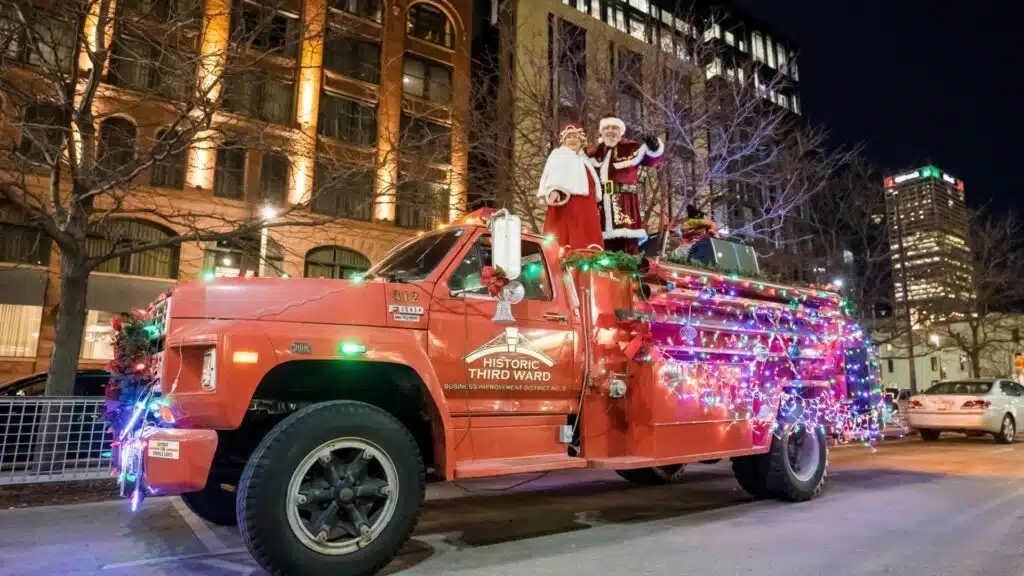 A red truch with Historic Third Ward on its door, Christmas lights on its body and Mrs and Santa Clause standing on top.
