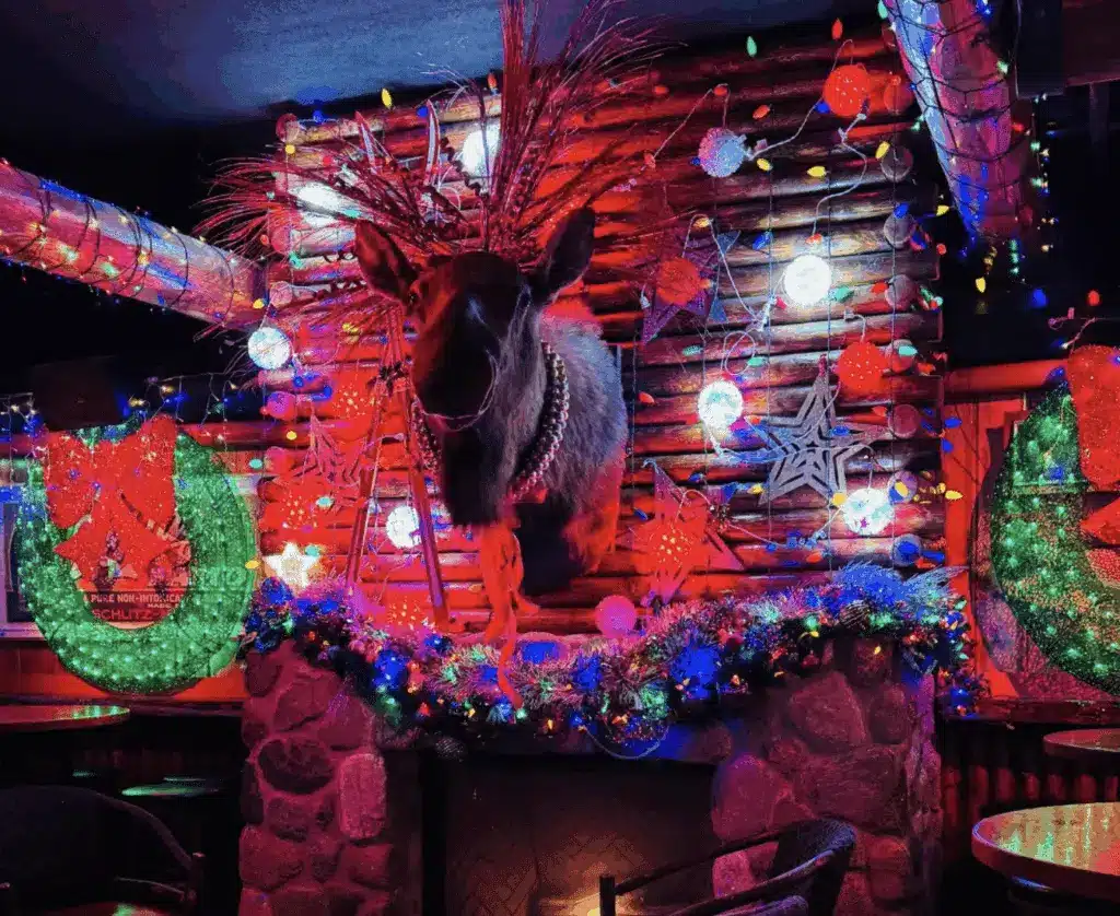 A head of a reindeer mounted on a wall decorated with Christmas elements such as star and garland