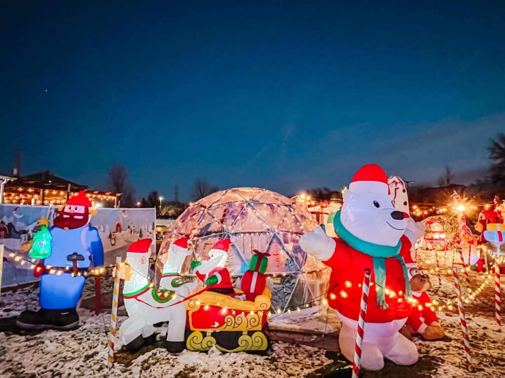 Glowing igloo dome decorated with string lights and inflatable polar bear in Santa hat