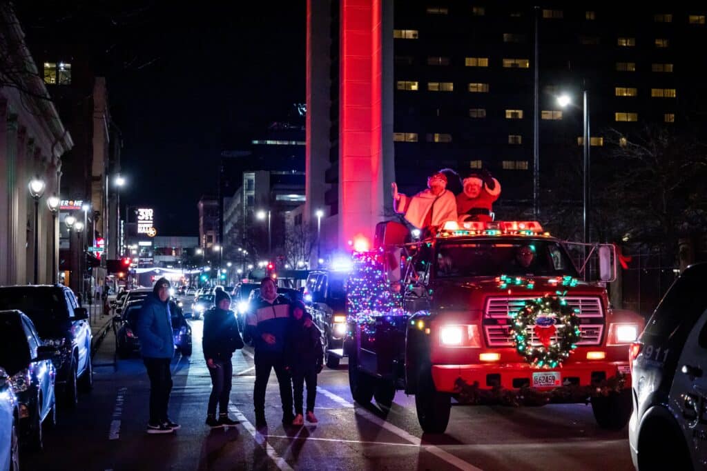 Santa and Mrs Clause riding a traditional red fire truck during Santa's Christmas Cavalcade in Downtown Milwaukee.