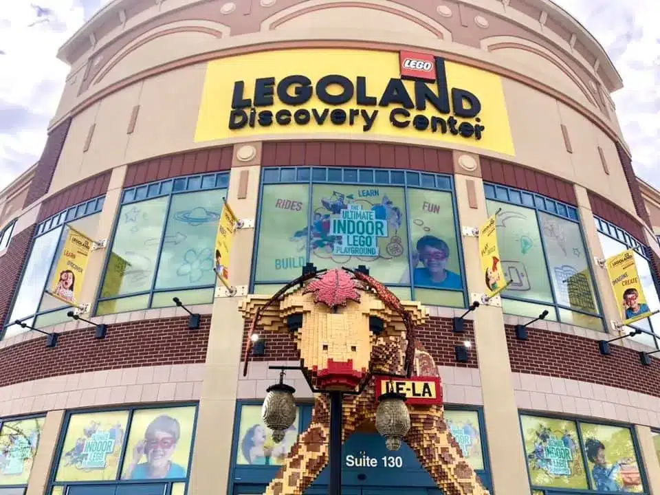 Exterior of LEGOLAND Discovery Center in Schaumburg with bright signage, large LEGO sculptures, and colorful window displays.
