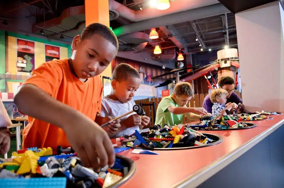 Children building LEGO creations at a hands-on play station inside LEGO Discovery Center.