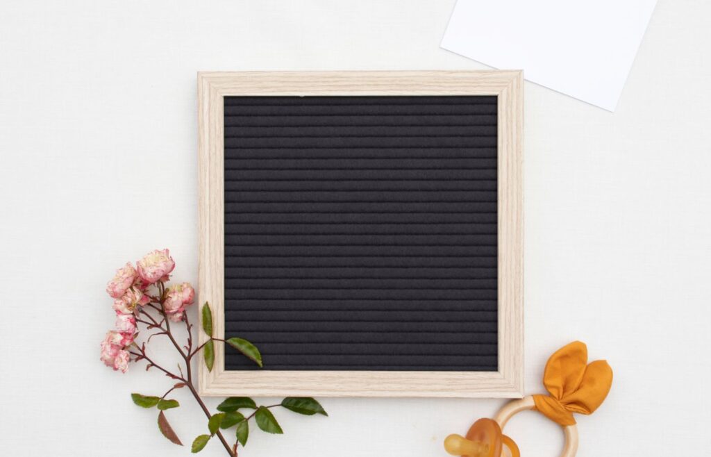 An empty letterboard with flower and pacifier 