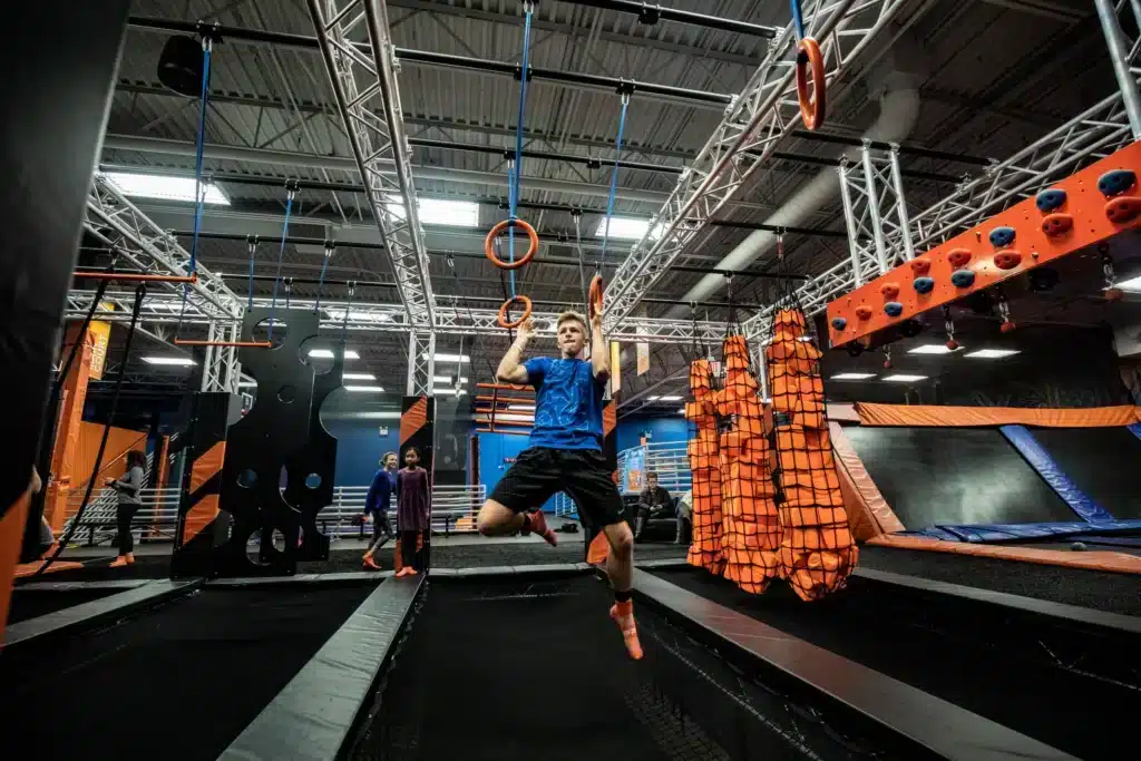 A child navigates hanging rings on the ninja course at Sky Zone Waukesha.
