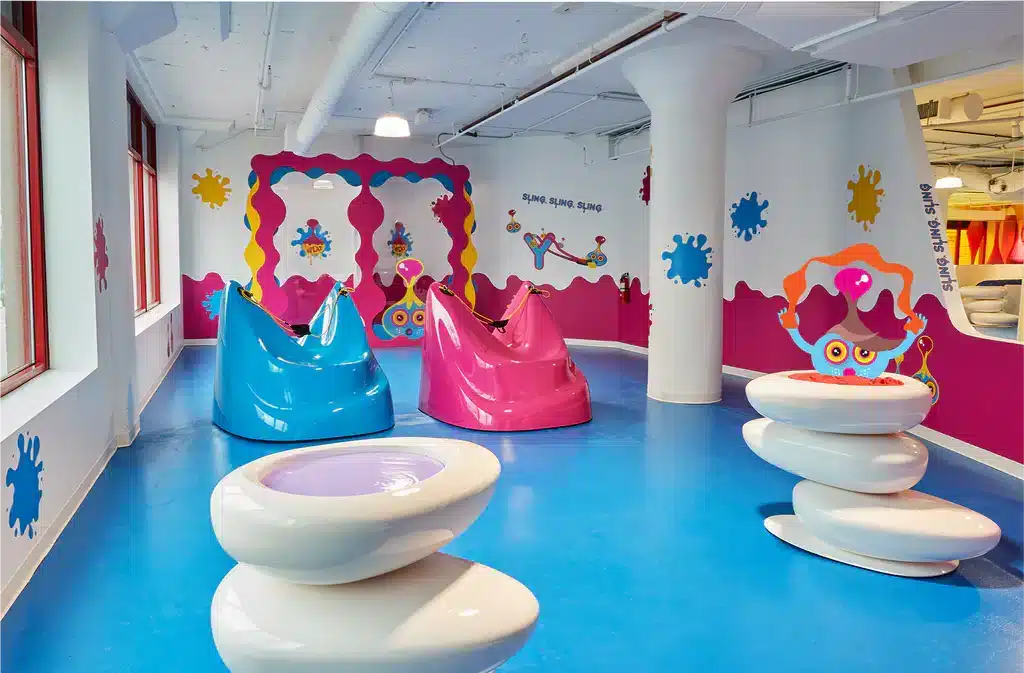A bright, colorful room at the Sloomoo Institute in Chicago featuring sculptural slime-themed chairs, playful wall art, and interactive sensory installations.