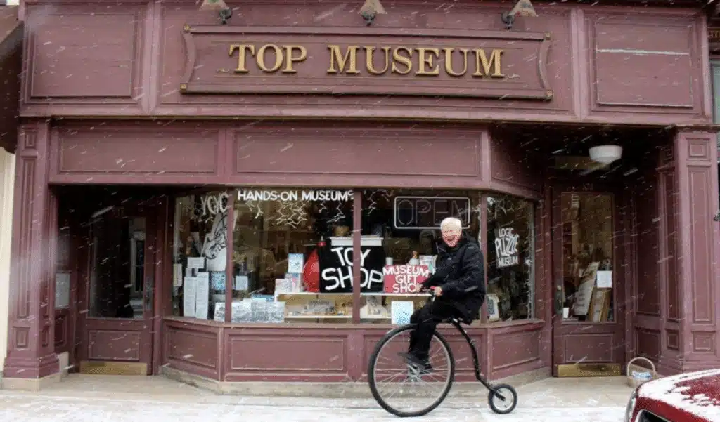 A man riding a unicycle in front of the Spinning Top and Yo-yo Museum in Burlington
