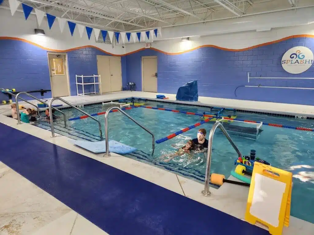 Children participating in swim lessons with instructors in the warm-water teaching pool at Splash Swim and Wellness.