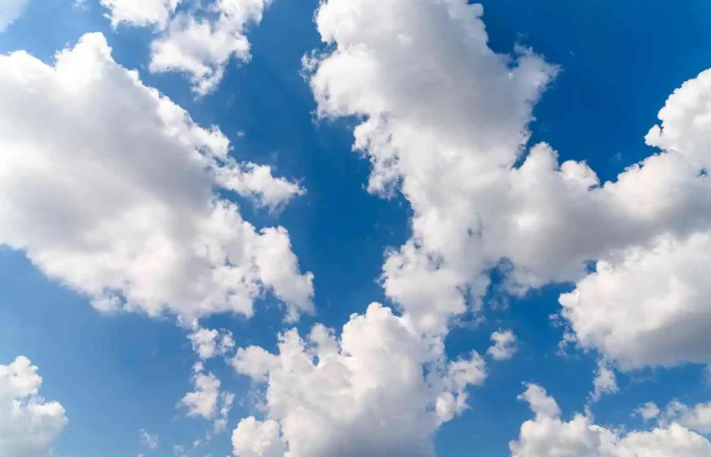 White fluffy clouds scattered across a bright blue sky.