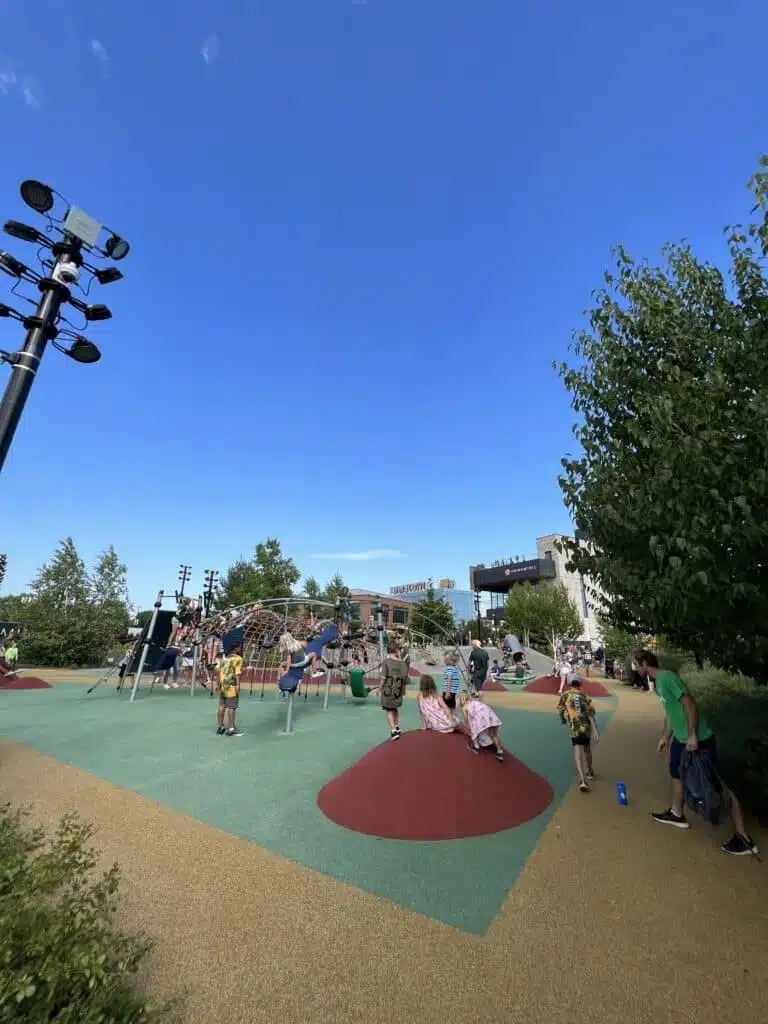 Kids sitting in red mounds while othes are climbing the climbing structures at Titletown District playground