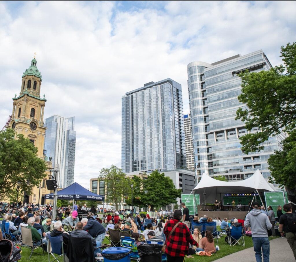 People sitting on chairs and grass while listening to a concert at the park