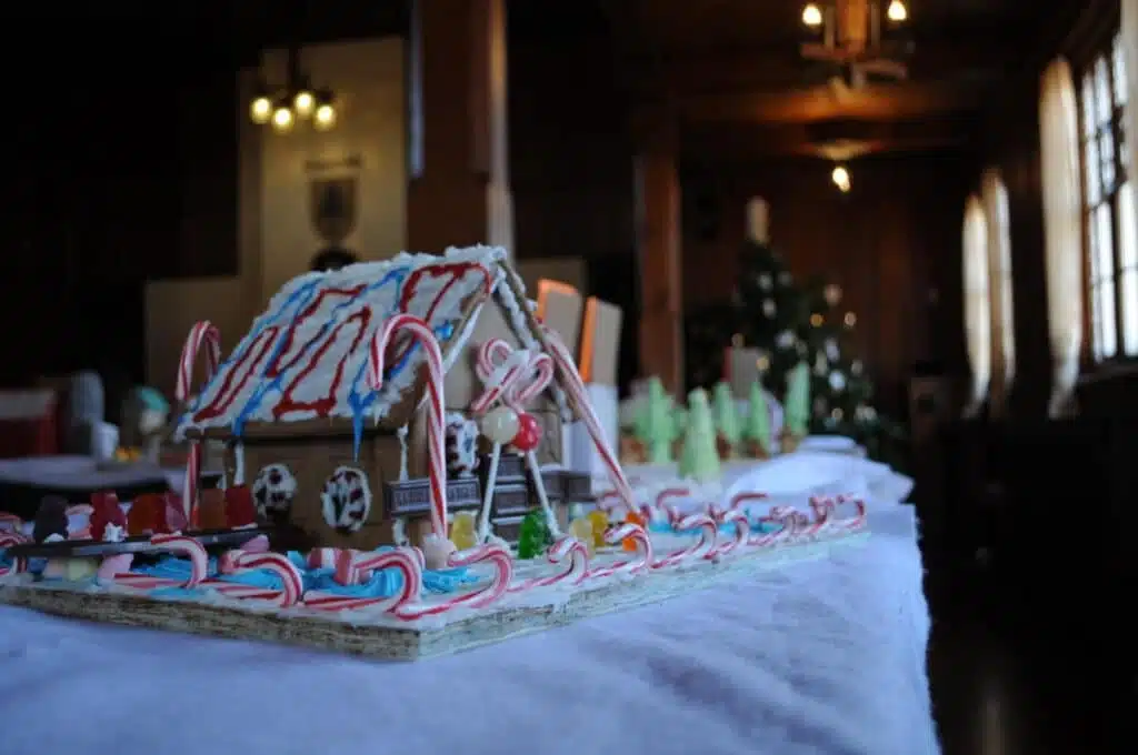 A gingerbread house decorated with small candy canes, lollipops and white icing.