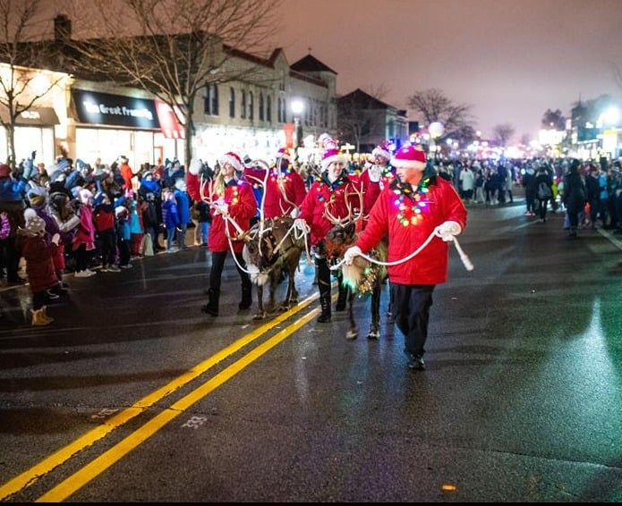 Men and women dressed as Santa's elves and holding  two reindeers as part of Whitefish Bay Holiday Stroll Parade.