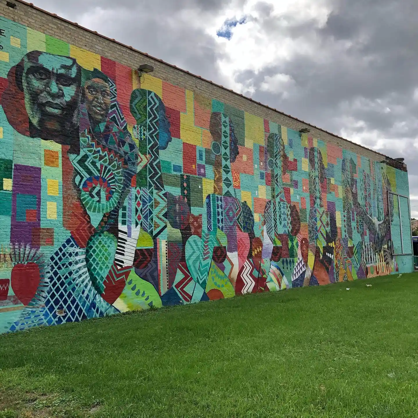 A mural that showcases different African faces and tribal design styles at the Wisconsin Black History museum