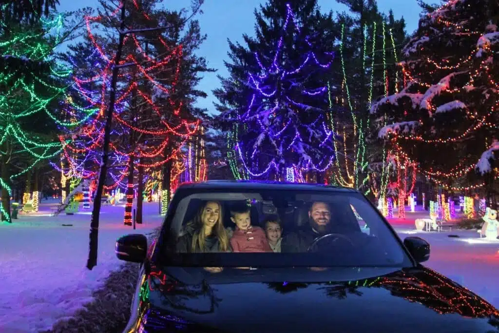 A family of four in a moving car and enjoying the holiday lights on tall trees at the Wisconsin Christmas Carnival of Lights in Caledonia Wisconsin