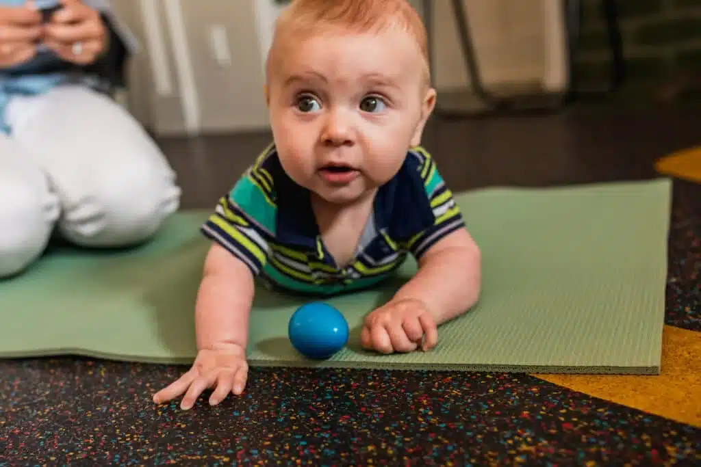 Baby on play mat explores rhythm with a small shaker 