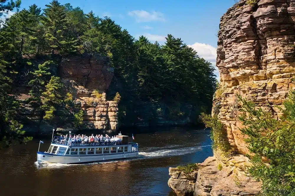 Tour boat travels between sandstone cliffs on a scenic Wisconsin Dells river tour.